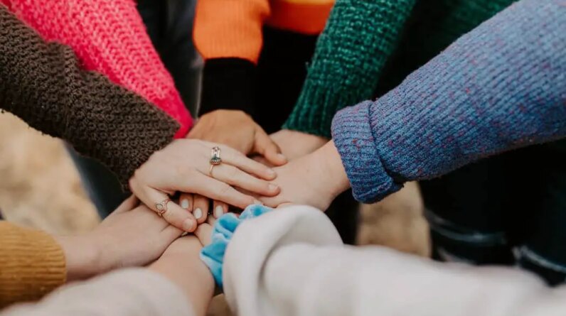 person in red sweater holding babys hand