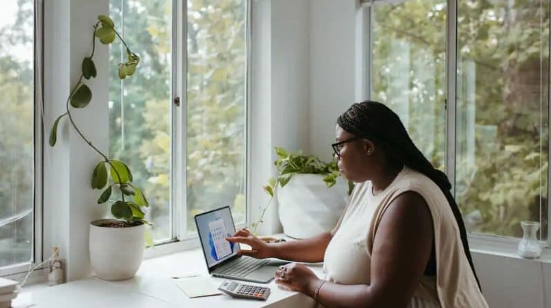 a woman sitting at a table with a laptop - linkedin marketing for freelancers