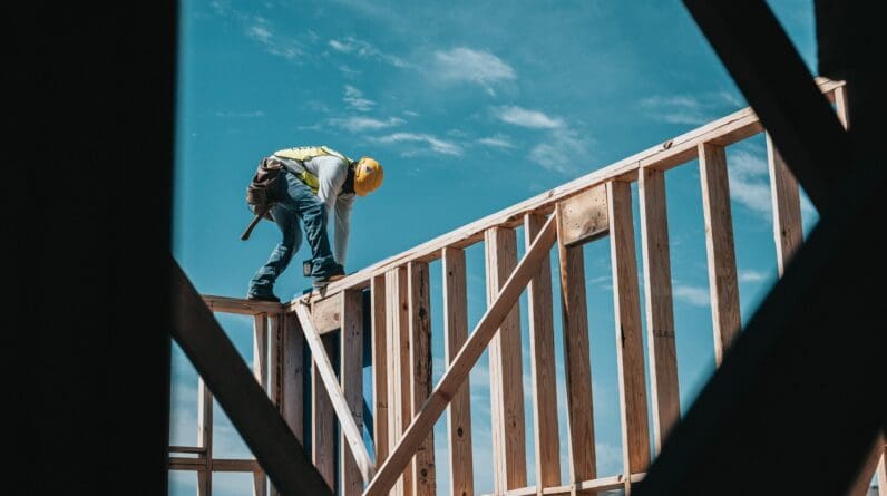 Man in yellow construction vest on wooden beams