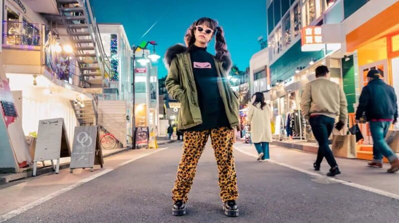 woman in green jacket stands and pose on street