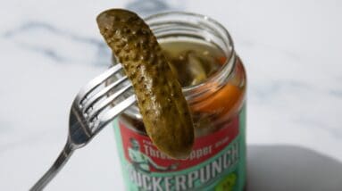 fork holding a pickle in front of jar