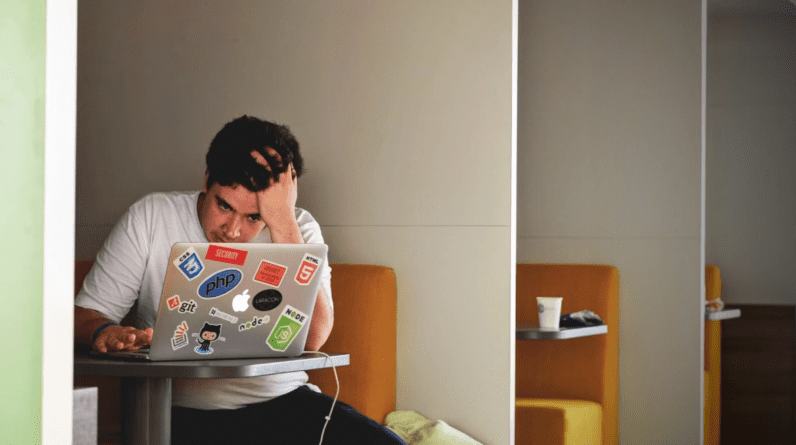 Man looking stressed behind laptop